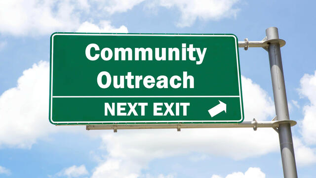 A road sign with "community outreach" next exit.