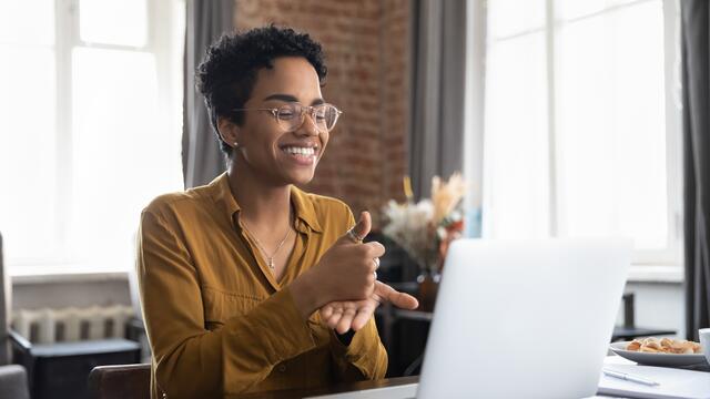 Adult using ASL to sign "help" over a laptop video call