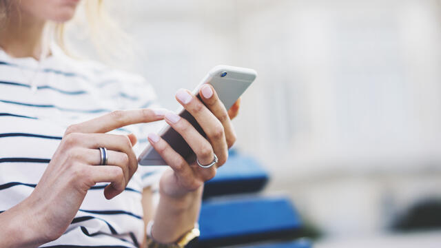 Close up of a person's hands using a cellphone, blurred background