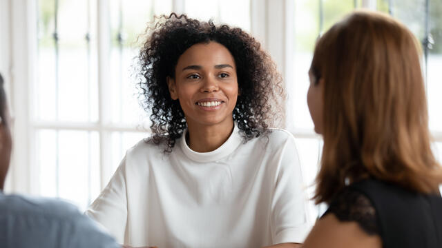 Three people in a meeting, one smiling