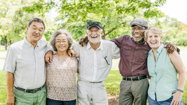 Five retired adults laughing outside.