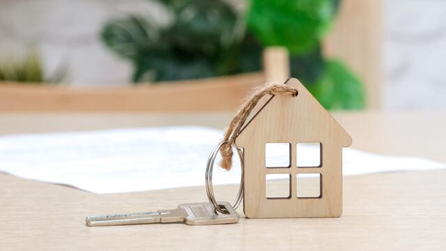 Wooden house keychain with a key on a contract lying on a table