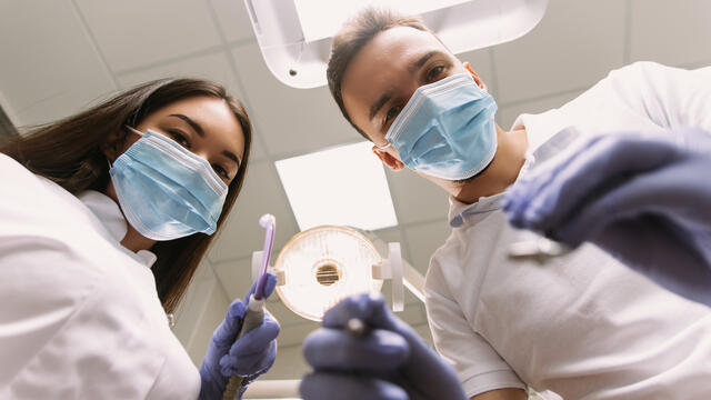 Patient's view of dental assistant and dentist performing a procedure