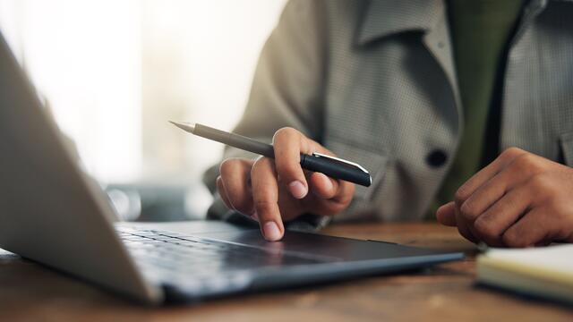 Close up of adult hands working on a laptop in an office