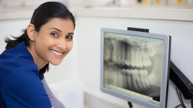 Smiling person next to a dental x-ray