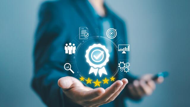Quality control concept:adult holds icons of people, documents, bullseye, graphs, gears around a blue ribbon