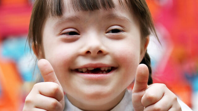 A smiling child gives thumbs up.
