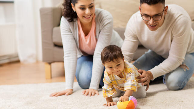 Two adults playing with a baby on the floor
