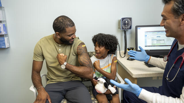 An adult and a child get a vaccine by a nurse in a clinic setting
