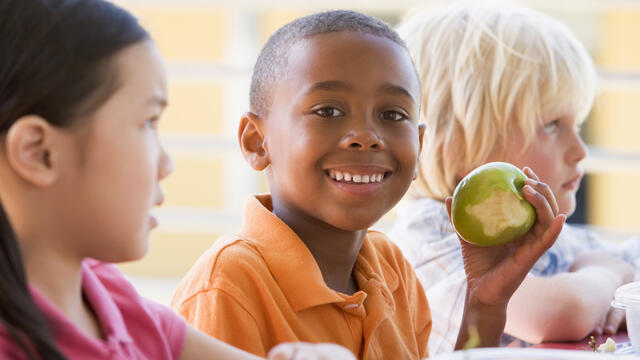A child takes a bite of an apple at school.