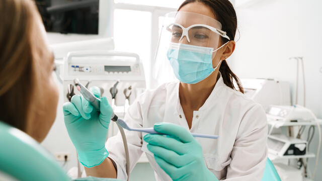 Dentist holding dental tool with patient