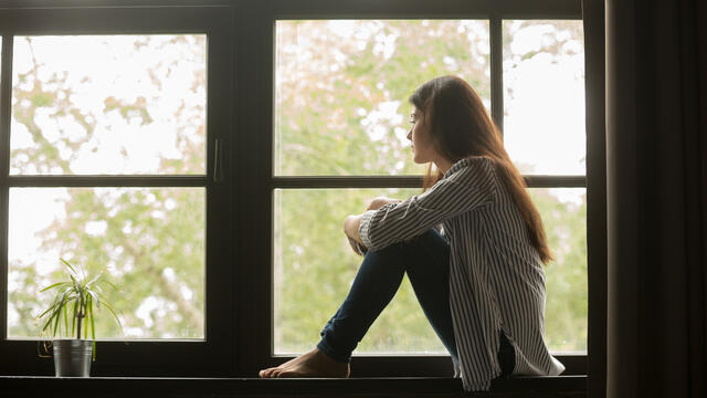 Sad person sitting next to a window