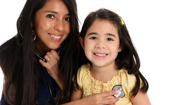 A smiling adult with stethoscope with a microphone over a young child's heart.