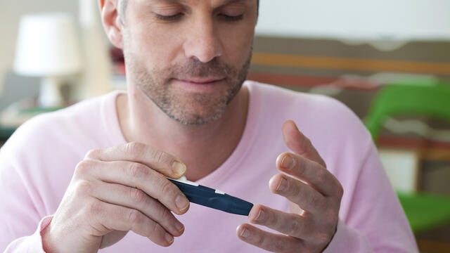 An adult performs an insulin test on his finger