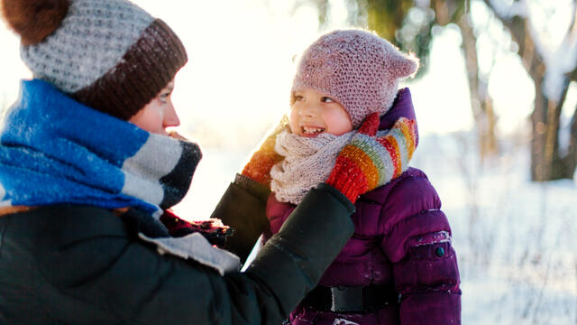 An adult and a toddler bundled up outside.