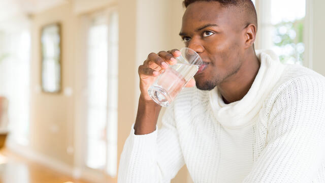 Adult drinking a glass of water at home