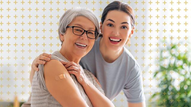 A younger adult with arm around an older adult who is showing vaccinated arm