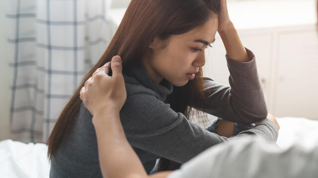 Adult arm on shoulder of sad teen