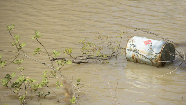 A chemical barrel floats in water.