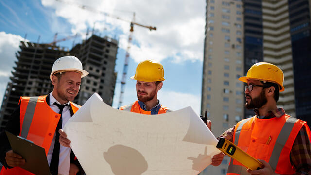Three construction inspectors review the blueprint.