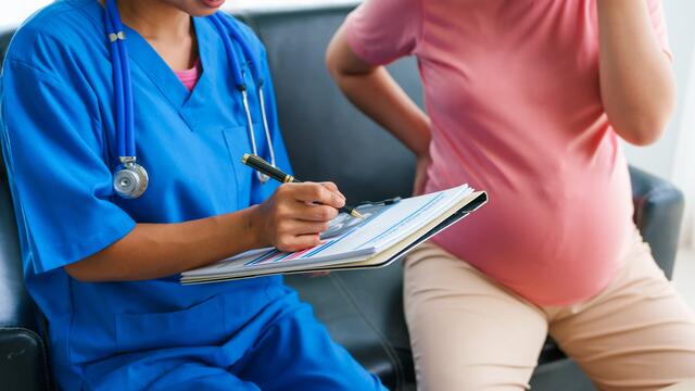 Doctor reviews notes with pregnant adult