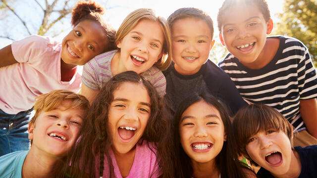 A close up of eight laughing children outside