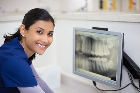 Smiling person next to a dental x-ray