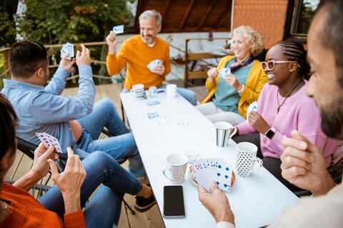 Group of friends play cards on a patio