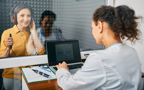 Tech giving an older adult a hearing test