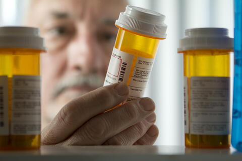 Older adult reading a prescription bottle
