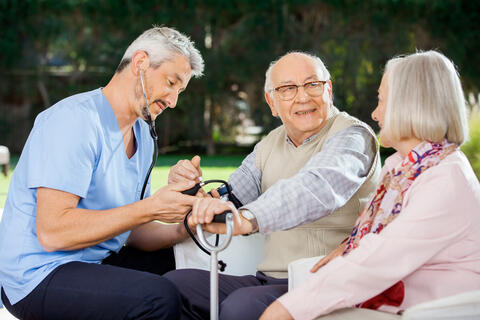 A medical professional doing a blood pressure reading on a patient outside.
