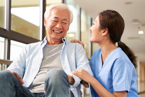An older adult laughing with their caregiver