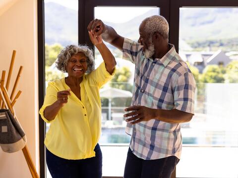 Two older adult dance at home