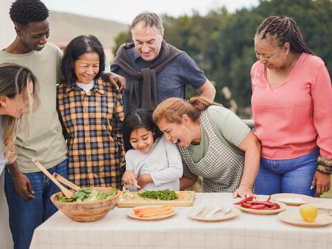 Seven family members around a table of food outside