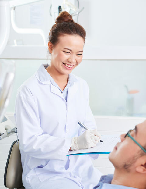 Smiling denting checking a patients teeth