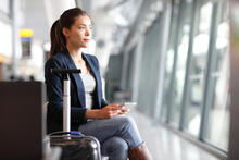 Adult in airport holds a tablet while waiting for a plane