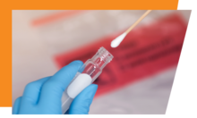Gloved hand holding a nasal swab for COVID-19