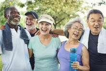 Five adults laughing together after exercising outside.