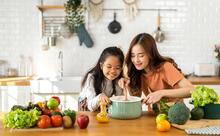 Adult teaching a child how to cook in their kitchen