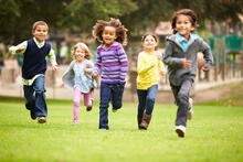 Five children race against each other at a playground.