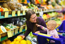 Adult smiles at baby in the shopping cart in produce aisle
