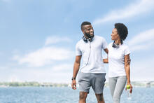A couple with arms around each other walk along the waterfront