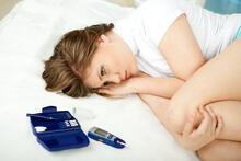 Sad adult lying on a bed next to a glucose meter