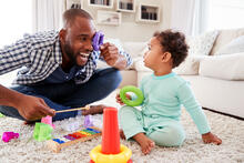 An adult happily plays with a toddler.