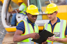 Two construction workers discuss the project on a site