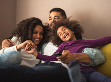 Family cuddled in the corner of a couch