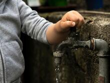 Person's hand on a water spigot
