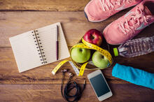 Items need for fitness such as notebook, shoes, water, fruit and phone.