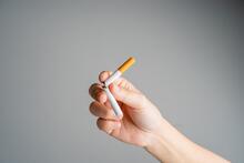 Hand holds broken cigarette to symbolize quitting