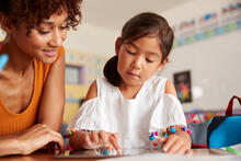 Teacher working with young child on tablet in school